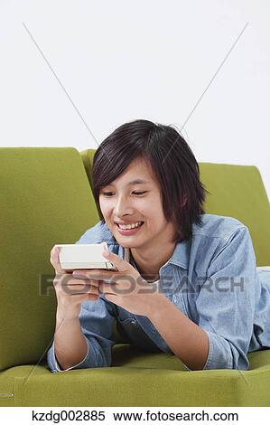 Stock Photography - Young man with phone on the sofa. Fotosearch