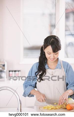 Young woman cutting vegetables in an open kitchen View Large Photo Image Stock Image - Young woman cutting vegetables in an open kitchen. Fotosearch