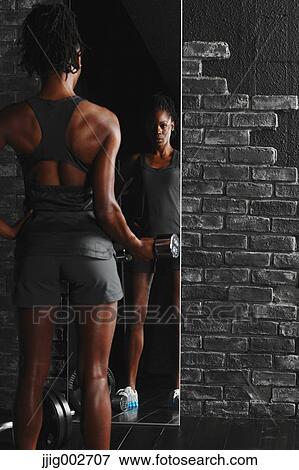 African Woman Exercising With Dumbbell in Front of a Mirror View Large Photo Image Stock Photo - African Woman Exercising With Dumbbell in Front of a Mirror . Fotosearch