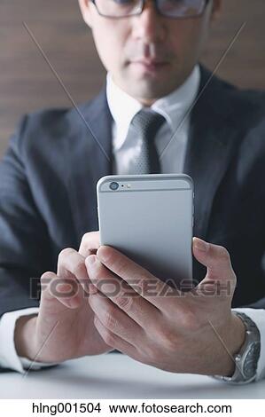 Japanese businessman working with large display smartphone View Large Photo Image Picture - Japanese businessman working with large display smartphone. Fotosearch