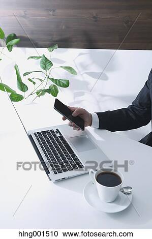 Stock Image - Japanese businessman working with large display smartphone. Fotosearch