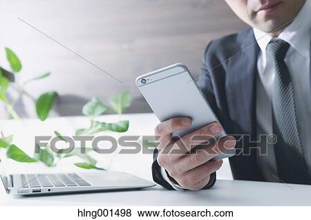 Stock Photo - Japanese businessman working with large display smartphone. Fotosearch
