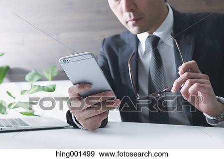 Japanese businessman working with large display smartphone View Large Photo Image Stock Photo - Japanese businessman working with large display smartphone. Fotosearch