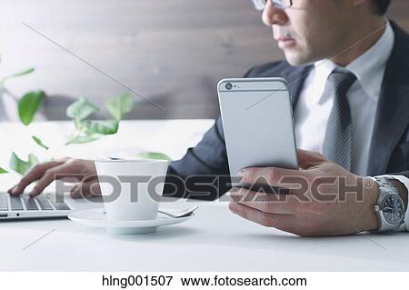 Japanese businessman working with large display smartphone View Large Photo Image Stock Photo - Japanese businessman working with large display smartphone. Fotosearch