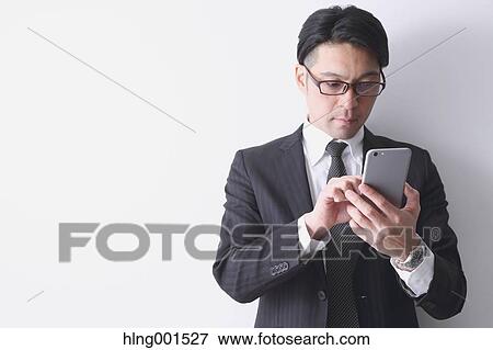 Japanese businessman working with large display smartphone View Large Photo Image Stock Photo - Japanese businessman working with large display smartphone. Fotosearch