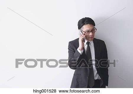 Stock Photo - Japanese businessman working with large display smartphone. Fotosearch