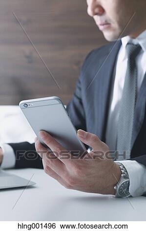 Stock Photograph - Japanese businessman working with large display smartphone. Fotosearch