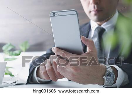 Japanese businessman working with large display smartphone View Large Photo Image Stock Photograph - Japanese businessman working with large display smartphone. Fotosearch