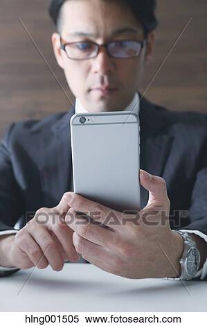 Japanese businessman working with large display smartphone View Large Photo Image Stock Photography - Japanese businessman working with large display smartphone. Fotosearch