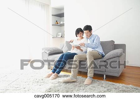 Stock Image - Japanese couple on the sofa with book. Fotosearch