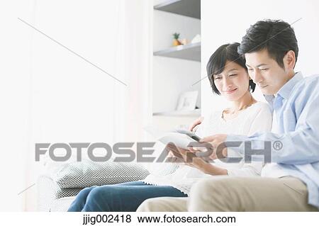 Stock Photo - Japanese couple on the sofa with book. Fotosearch