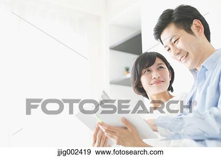 Japanese couple on the sofa with book View Large Photo Image Stock Photo - Japanese couple on the sofa with book. Fotosearch