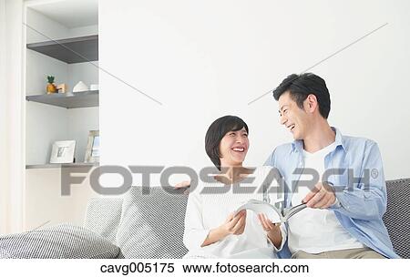 Stock Photography - Japanese couple on the sofa with book. Fotosearch