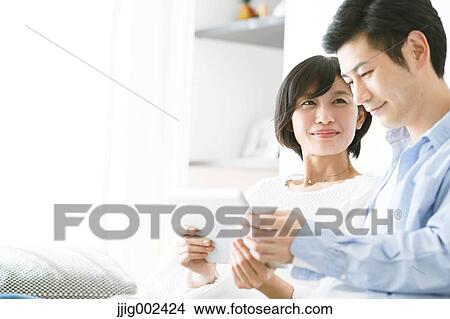 Japanese couple on the sofa with tablet View Large Photo Image Picture - Japanese couple on the sofa with tablet. Fotosearch