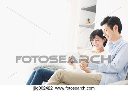 Japanese couple on the sofa with tablet View Large Photo Image Stock Image - Japanese couple on the sofa with tablet. Fotosearch
