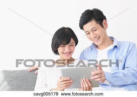 Japanese couple on the sofa with tablet View Large Photo Image Stock Photo - Japanese couple on the sofa with tablet. Fotosearch