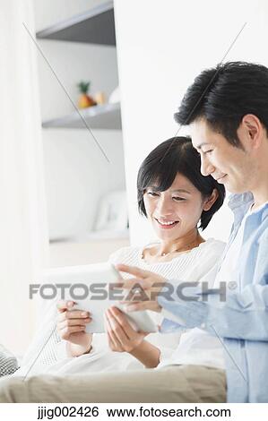 Japanese couple on the sofa with tablet View Large Photo Image Stock Photograph - Japanese couple on the sofa with tablet. Fotosearch