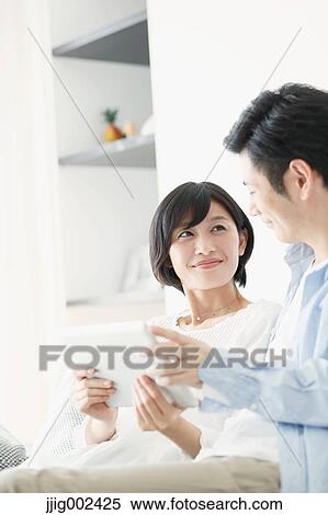 Stock Photography - Japanese couple on the sofa with tablet. Fotosearch