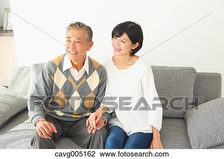 Stock Image - Japanese senior and daughter on the sofa. Fotosearch