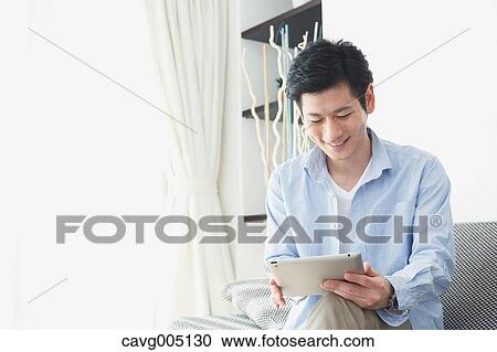 Japanese young man on the sofa with tablet View Large Photo Image Stock Image - Japanese young man on the sofa with tablet. Fotosearch