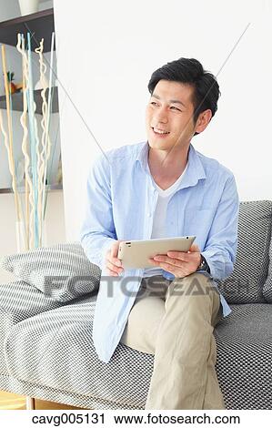Japanese young man on the sofa with tablet View Large Photo Image Stock Image - Japanese young man on the sofa with tablet. Fotosearch