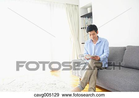 Japanese young man on the sofa with tablet View Large Photo Image Stock Photo - Japanese young man on the sofa with tablet. Fotosearch