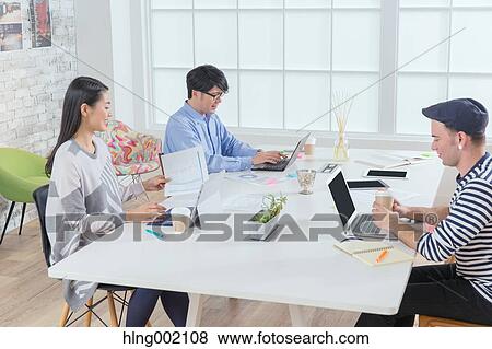 Stock Photo - Multi-ethnic business people working in modern office. Fotosearch