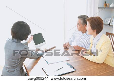 Picture - Senior Japanese couple consulting with financial planner. Fotosearch