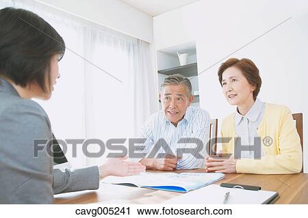 Stock Image - Senior Japanese couple consulting with financial planner. Fotosearch