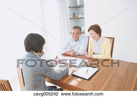 Stock Image - Senior Japanese couple consulting with financial planner. Fotosearch