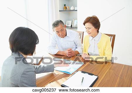 Stock Photo - Senior Japanese couple consulting with financial planner. Fotosearch