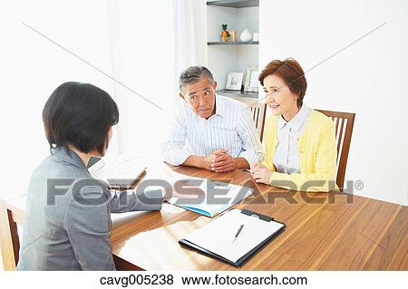 Stock Photo - Senior Japanese couple consulting with financial planner. Fotosearch