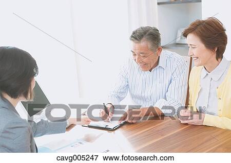 Stock Photo - Senior Japanese couple consulting with financial planner. Fotosearch
