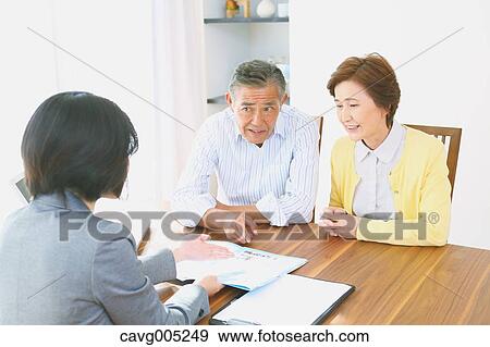 Stock Photo - Senior Japanese couple consulting with financial planner. Fotosearch