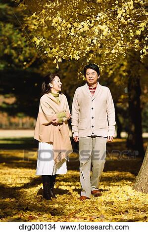 Picture - Senior Japanese couple in a city park in Autumn. Fotosearch