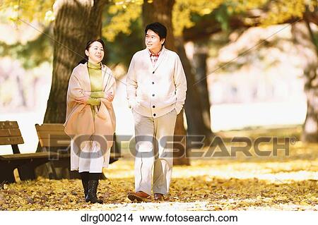 Picture - Senior Japanese couple in a city park in Autumn. Fotosearch