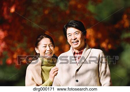 Stock Image - Senior Japanese couple in a city park in Autumn. Fotosearch