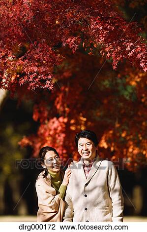 Stock Image - Senior Japanese couple in a city park in Autumn. Fotosearch