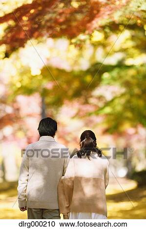 Stock Image - Senior Japanese couple in a city park in Autumn. Fotosearch