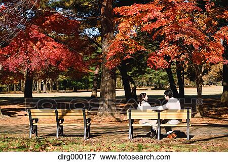Stock Photo - Senior Japanese couple sitting on a bench in a city park. Fotosearch