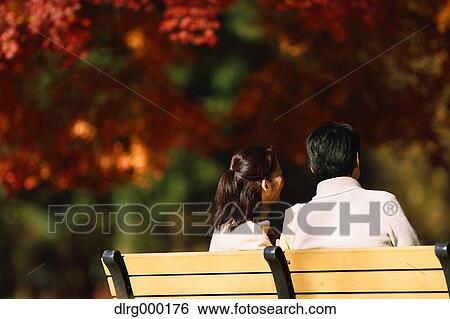 Stock Photograph - Senior Japanese couple sitting on a bench in a city park. Fotosearch