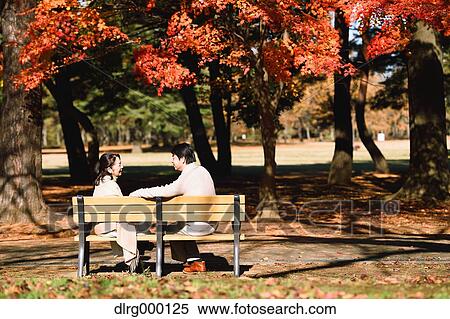 Stock Photography - Senior Japanese couple sitting on a bench in a city park. Fotosearch