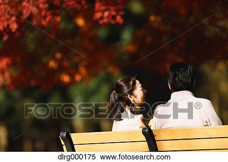 Stock Photography - Senior Japanese couple sitting on a bench in a city park. Fotosearch