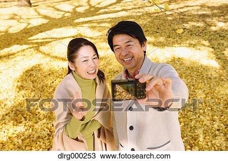 Senior Japanese couple taking pictures in a city park in Autumn View Large Photo Image Stock Image - Senior Japanese couple taking pictures in a city park in Autumn. Fotosearch