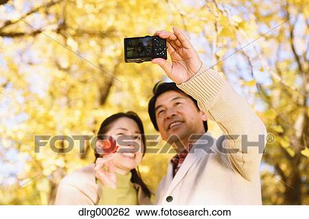 Senior Japanese couple taking pictures in a city park in Autumn View Large Photo Image Stock Image - Senior Japanese couple taking pictures in a city park in Autumn. Fotosearch