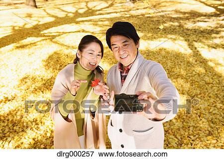 Senior Japanese couple taking pictures in a city park in Autumn View Large Photo Image Stock Photo - Senior Japanese couple taking pictures in a city park in Autumn. Fotosearch