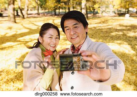 Senior Japanese couple taking pictures in a city park in Autumn View Large Photo Image Stock Photo - Senior Japanese couple taking pictures in a city park in Autumn. Fotosearch