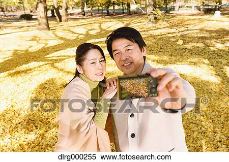 Senior Japanese couple taking pictures in a city park in Autumn View Large Photo Image Stock Photography - Senior Japanese couple taking pictures in a city park in Autumn. Fotosearch