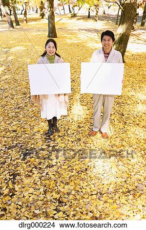 Picture - Senior Japanese couple with whiteboard in a city park. Fotosearch