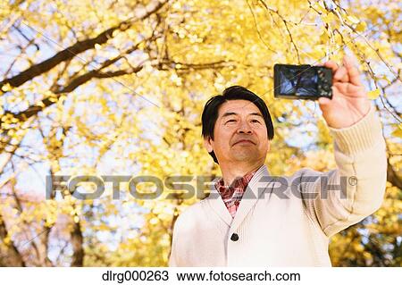 Senior Japanese man taking a selfie in a city park in Autumn View Large Photo Image Stock Image - Senior Japanese man taking a selfie in a city park in Autumn. Fotosearch